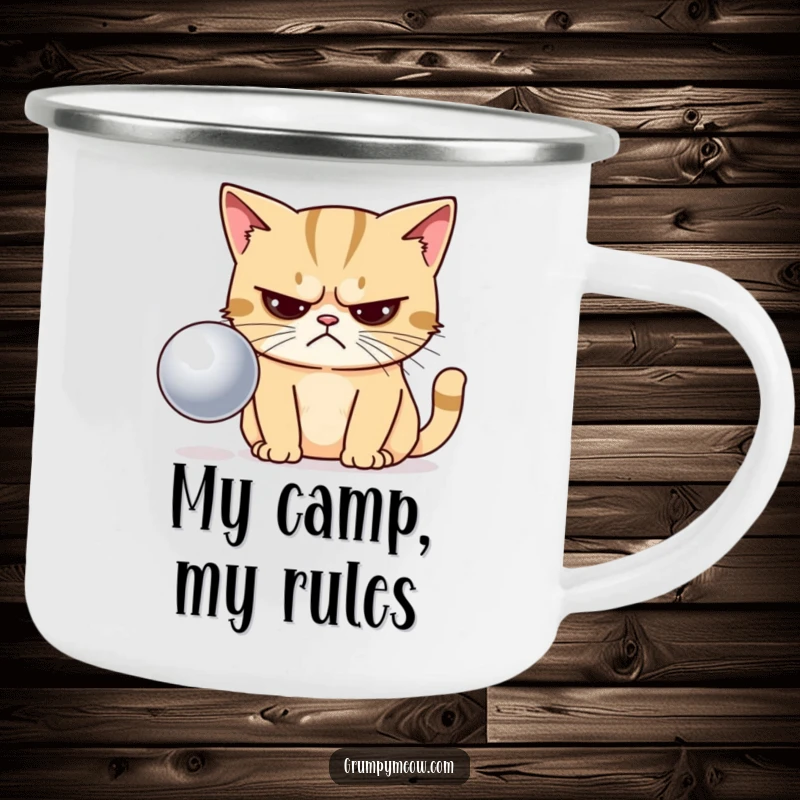 Funny camping mug featuring a grumpy cat with narrowed eyes, looking disapprovingly at a shiny ball in nature.