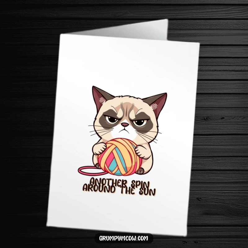 Funny Free Printable Birthday Card: Grumpy cat with narrowed eyes judges a brightly colored ball of yarn.