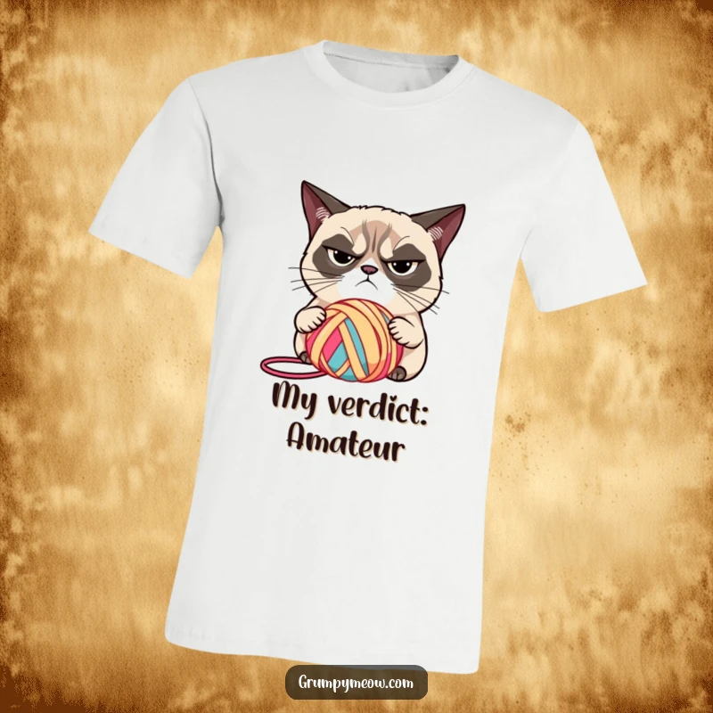 Funny grumpy cat with narrowed eyes, judging a brightly colored ball of yarn on a t-shirt, a classic funny gift.